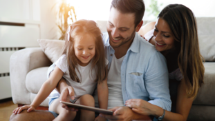 Ein Mann, eine Frau und ein Kind schauen auf ein Tablet.